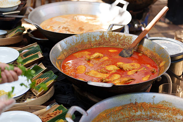 Street vendor preparing delicious rendang in large wok