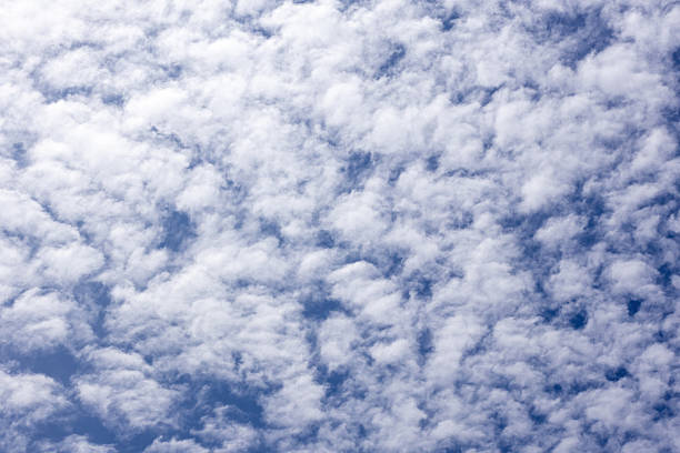 Stunning scattered white clouds against a vibrant blue sky, creating an ethereal abstract background texture. Ideal for tranquil digital art, graphic design, and captivating visual projects.