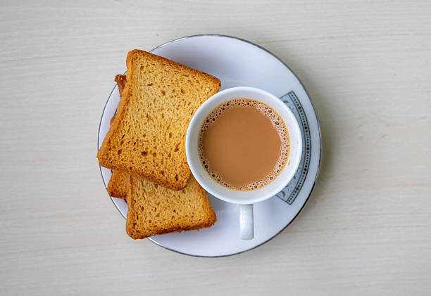 istock Hot milk tea with frothy bubbles and crispy rusk biscuits on wood background. Delicious Dudh Cha from top view for your projects. 2225937721