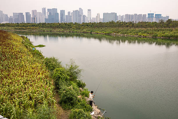 An Asian elementary school student is fishing by the lake