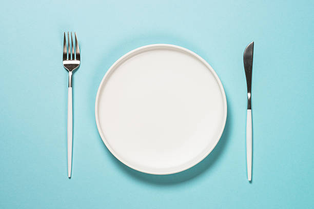 istock Table setting with white plate and cutlery on blue. 2225941259
