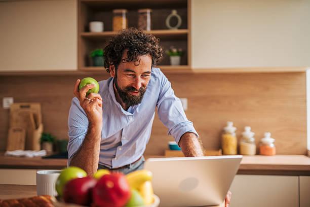 istock Happy freelancer eating apple and working from home in kitchen 2225944121