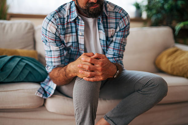 istock Worried man sitting on sofa at home holding hands 2225944371