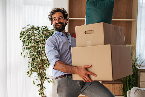 istock Man carrying stack of cardboard boxes moving into new home 2225944678