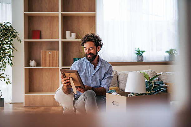 istock Smiling man looking at photo frame after moving into new home 2225945097