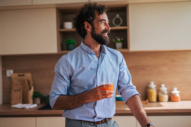 istock Smiling bearded man drinking orange juice in kitchen 2225945719