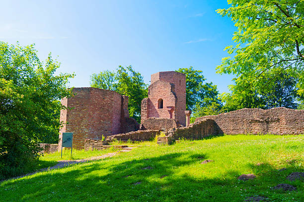 Historic ruins of the Monastery of St. Michael in Heidelberg, set amidst lush greenery and bright blue skies during midday.