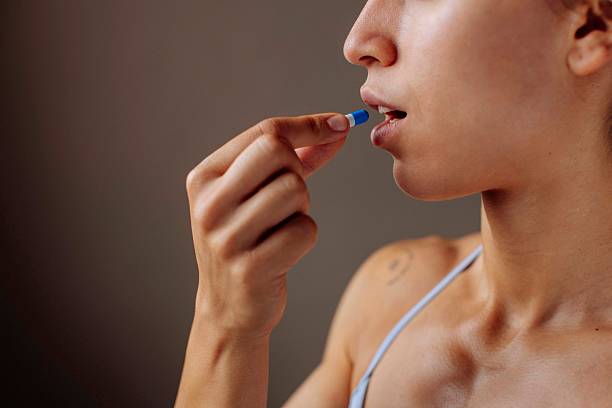 istock Muscular Sportswoman Taking Blue Supplement Capsule 2225947797