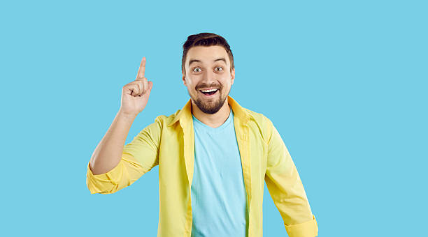 istock Man standing isolated on a blue background has an idea, smiles and points his finger up 2225948795