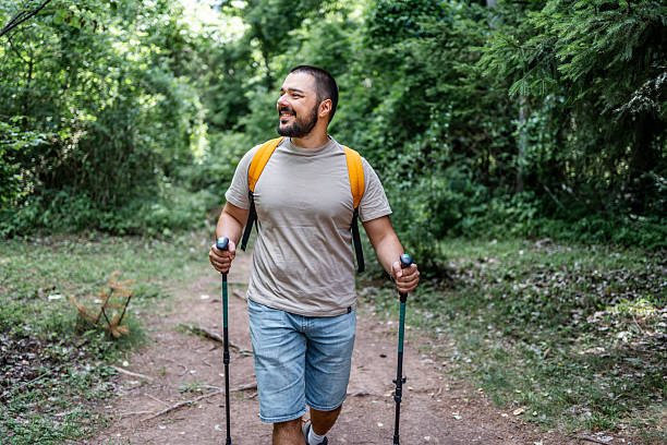 istock Smiling hiker walking in the forest using trekking poles 2225949681