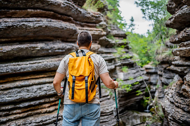 istock Hiker exploring narrow canyon with trekking poles and backpack 2225950064