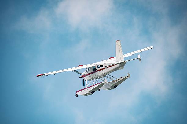 istock Rear angle of a white and red floatplane banking in flight against a clear blue sky 2225952571