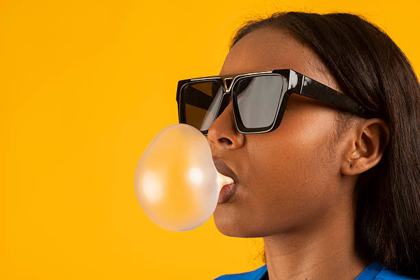 istock Fashionable model blowing bubblegum on yellow background 2225956030