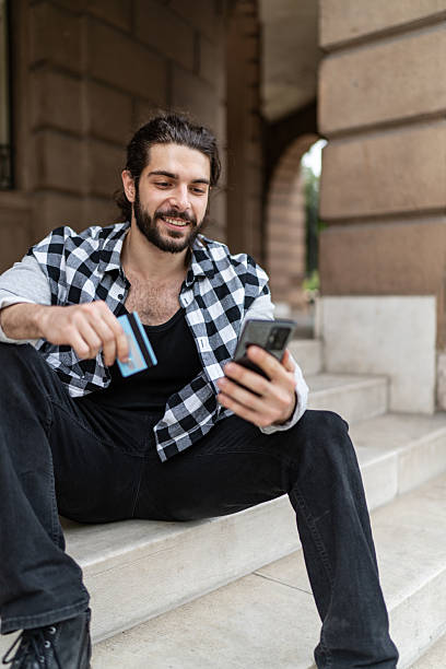 istock Young man shopping online using smartphone and credit card 2225966392