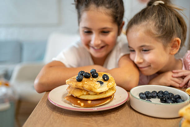 istock Two children enjoying pancakes with blueberries at home in a cozy setting 2225971346