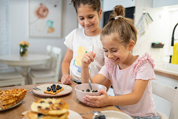 istock Two children enjoying a nutritious blueberry breakfast at a home kitchen 2225971856