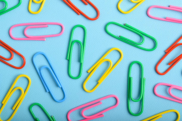 Colorful paper clips isolated on light blue background, flat lay, top view