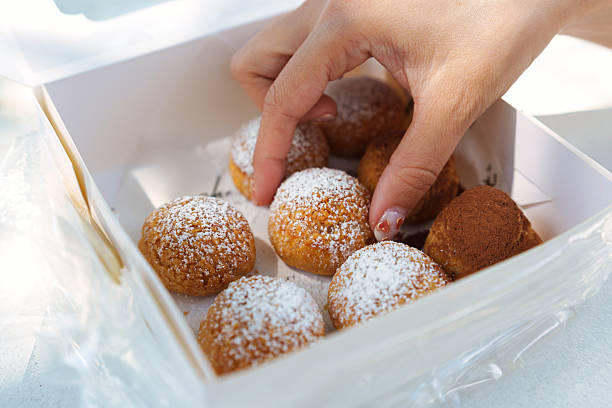 istock Woman hand picking choux cream dessert from bakery box 2225973031