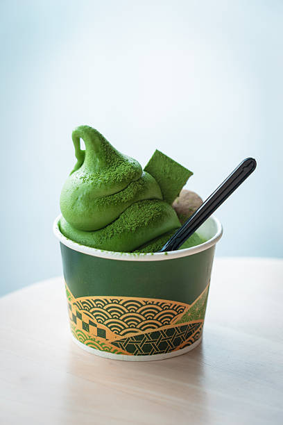 Matcha ice cream in a decorated cup, topped with mochi and a spoon, ready to be enjoyed