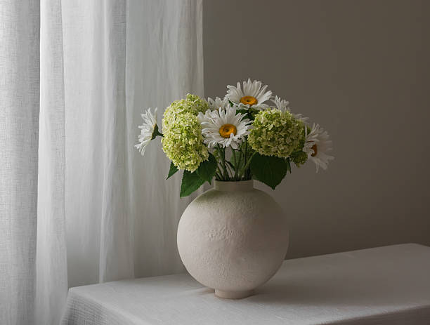 istock A bouquet of hydrangeas and daisies in a round ceramic vase on a table with a white tablecloth 2225978378