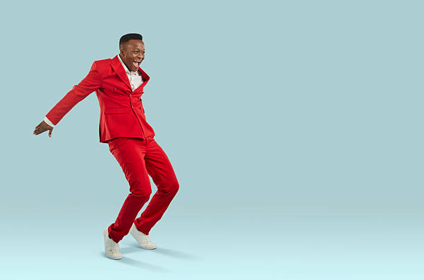 istock Happy excited African man in red suit dancing and having fun on copy space background 2225978992