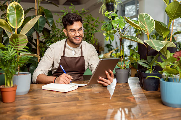 istock Flower shop assistant analyzing online orders and looking contented 2225980788