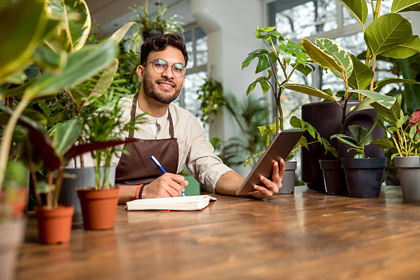 istock Young male shop assistant making notes while working in the flower shop 2225980803
