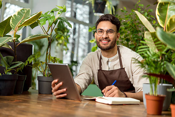 istock Young male shop assistant making notes while working in the flower shop 2225980804