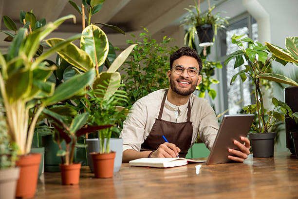 istock Young male shop assistant making notes while working in the flower shop 2225980813