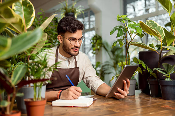 istock Flower shop assistant analyzing online orders and looking contented 2225980814