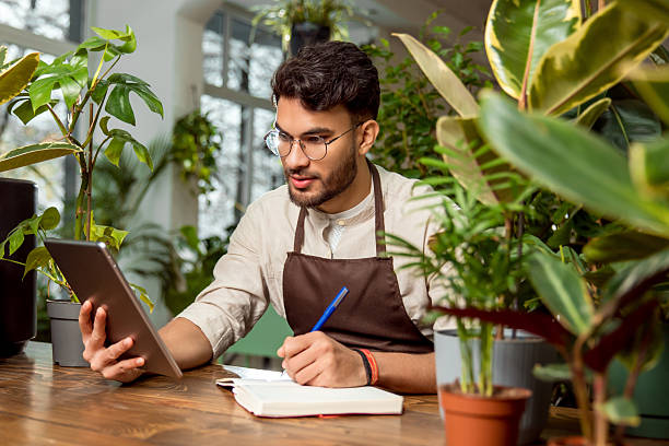 istock Flower shop assistant analyzing online orders and looking contented 2225980840