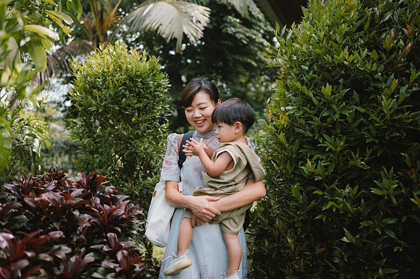 A woman lovingly holds her child while enjoying the lush greenery of a tranquil resort, capturing the essence of sustainable quiet luxury travel in harmony with nature.