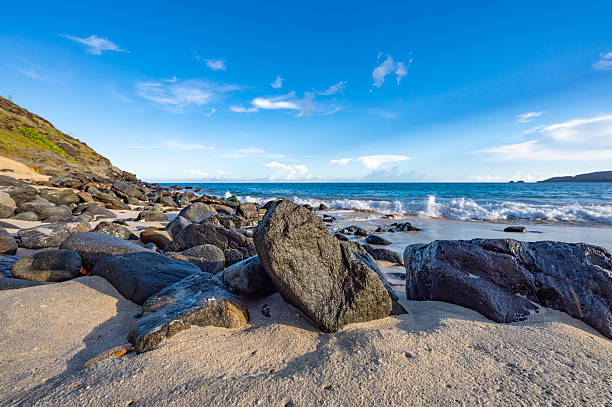 Stunning view of a rocky seaside where the ocean waves gracefully crash upon the stones. The natural landscape offers a serene and tranquil atmosphere by the water's edge.