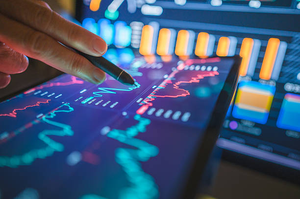 istock Hand holding a stylus interacting with a vibrant digital tablet displaying complex financial data graphs, symbolizing AI-driven data analysis or secure coding for fintech 2225984341