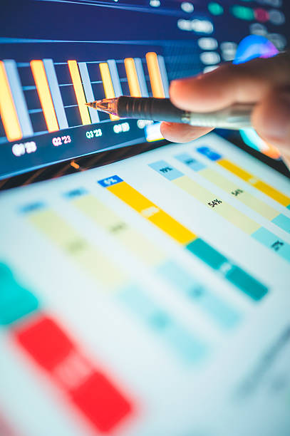 istock A hand operating a stylus on a tablet screen, showing glowing blue and red financial charts links to data security analysis, the development of AI systems for predictive analytics, or secure coding practices within digital environments. 2225984344