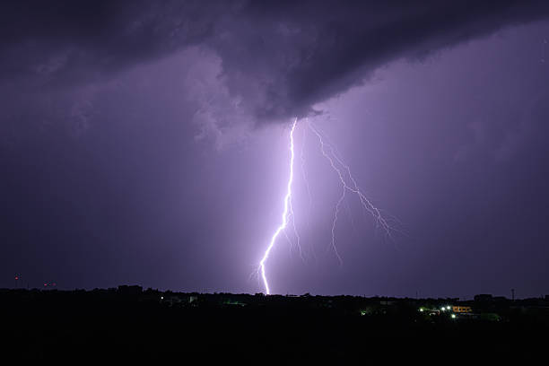 istock Single powerful lightning bolt hitting the ground from storm clouds at night. 2225985797