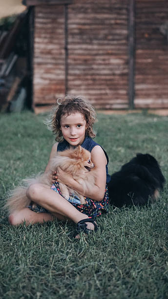 istock 8-year-old girl holding fluffy spitz dog with second black spitz nearby 2225990138