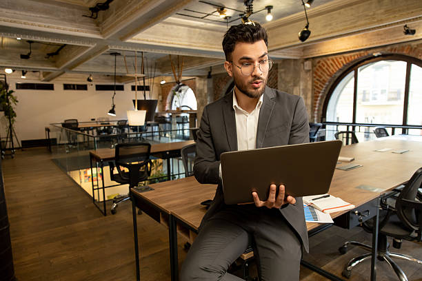 istock Young man with laptop looking surprised and emotional 2225991149