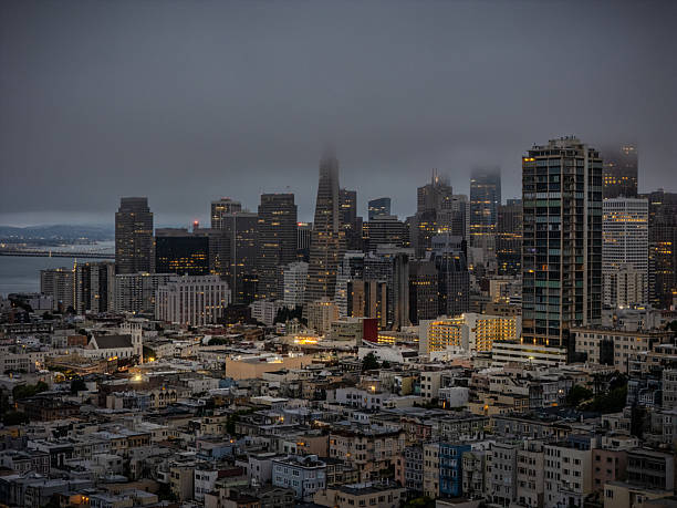 An aerial view of the San Francisco financial district with skyscrapers cloaked in fog.