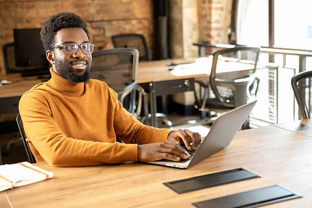 istock Bearded man in glasses typing on laptop working online from stylish office 2225991361