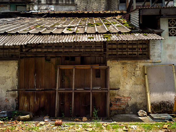 istock Weathered Building with Moss-Covered Metal Roof and Exposed Brickwork 2225993322