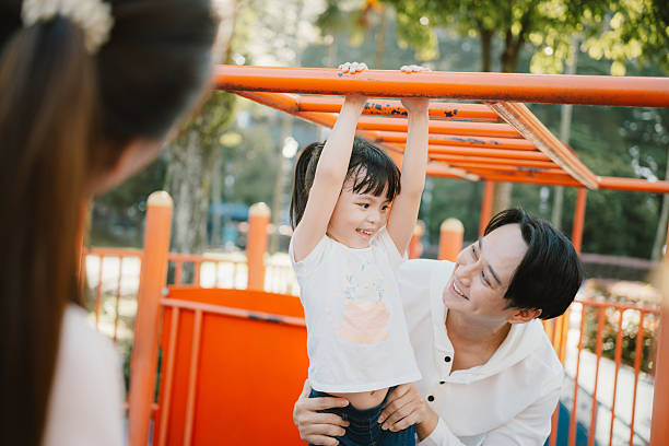 istock Asian Father Helping Daughter on Monkey Bars at Playground 2225993794
