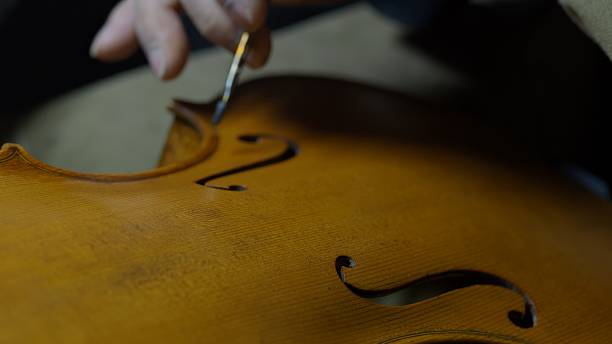 istock Skilled craftsman varnishing wooden cello, meticulously brushing lacquer surface while restoring delicate musical instrument 2225994897