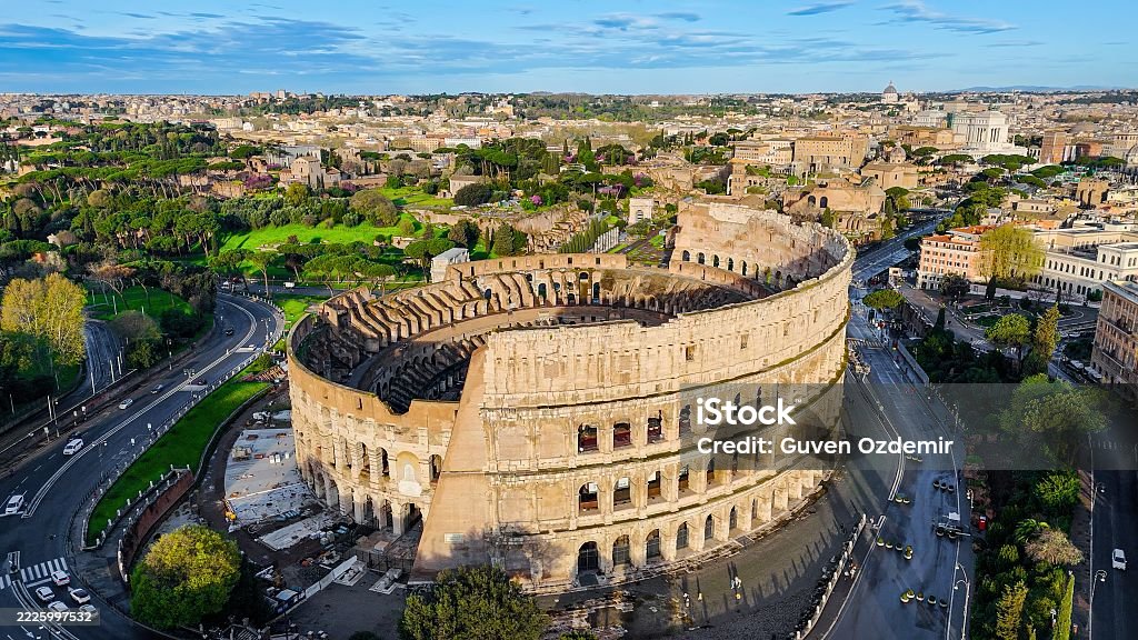 Aerial view of the ancient Colosseum in Rome with panoramic cityscape, iconic Roman amphitheater from different angles including top-down detail, Historical architecture and tourism concept for editorial and travel design This photo captures dynamic aerial footage of the Colosseum in Rome, Italy, emphasizing its circular form, layered stone arches, and the surrounding historic urban landscape. Sweeping shots transition from wide panoramic views of the Roman cityscape to dramatic close-ups of the Colosseum’s interior chambers, showcasing its grand scale and architectural complexity. As one of the most recognizable landmarks of the Roman Empire, this amphitheater stands as a symbol of classical heritage and historical significance, making the footage ideal for documentaries, travel features, or educational media. Coliseum - Rome Stock Photo Aerial view of the ancient Colosseum in Rome with panoramic cityscape, iconic Roman amphitheater from different angles including top-down detail, Historical architecture and tourism concept for editorial and travel design This photo captures dynamic aerial footage of the Colosseum in Rome, Italy, emphasizing its circular form, layered stone arches, and the surrounding historic urban landscape. Sweeping shots transition from wide panoramic views of the Roman cityscape to dramatic close-ups of the Colosseum’s interior chambers, showcasing its grand scale and architectural complexity. As one of the most recognizable landmarks of the Roman Empire, this amphitheater stands as a symbol of classical heritage and historical significance, making the footage ideal for documentaries, travel features, or educational media. Coliseum - Rome Stock Photo