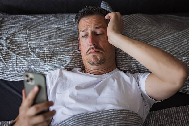 istock Stressed man checking smartphone in bed early in the morning 2225999000