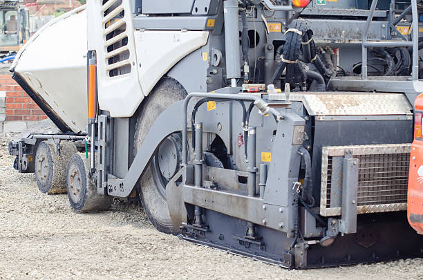 istock Construction workers in high-visibility gear are applyin gfresh hot asphalt to roadway surface 2225999364
