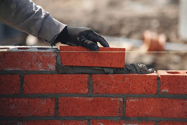 istock Close-up of skilled bricklayer working on construction site laying bricks for wall construction 2226000010
