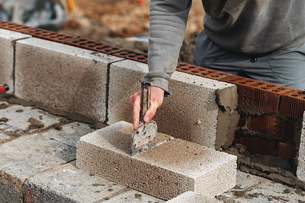 istock Builder cutting concrete block with chisel and hammer to right size 2226003273