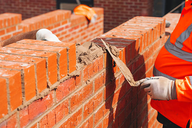 istock Industrial bricklayer laying bricks and concrete blocks on cement mix mortar on construction site 2226003523