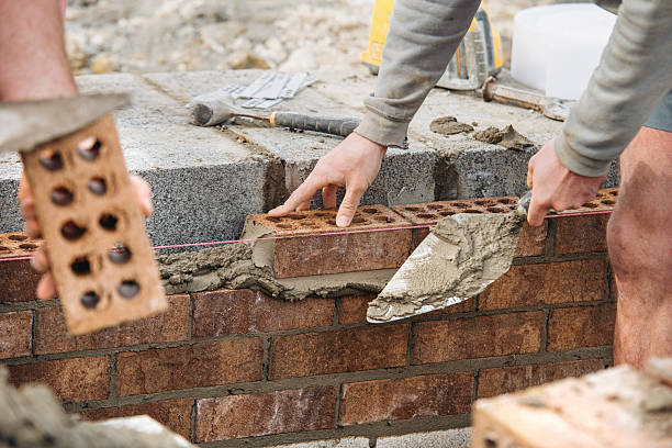 istock Industrial bricklayer laying bricks and concrete blocks on cement mix mortar on construction site 2226003800